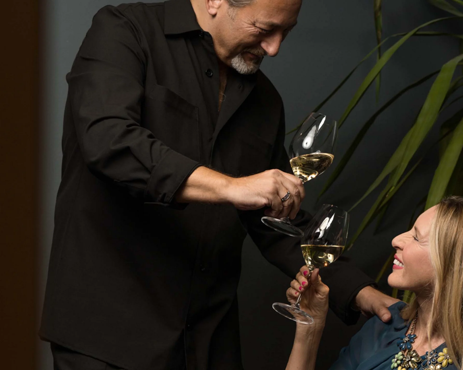 Mann und Frau stoßen mit Weingläsern an und lächeln sich an