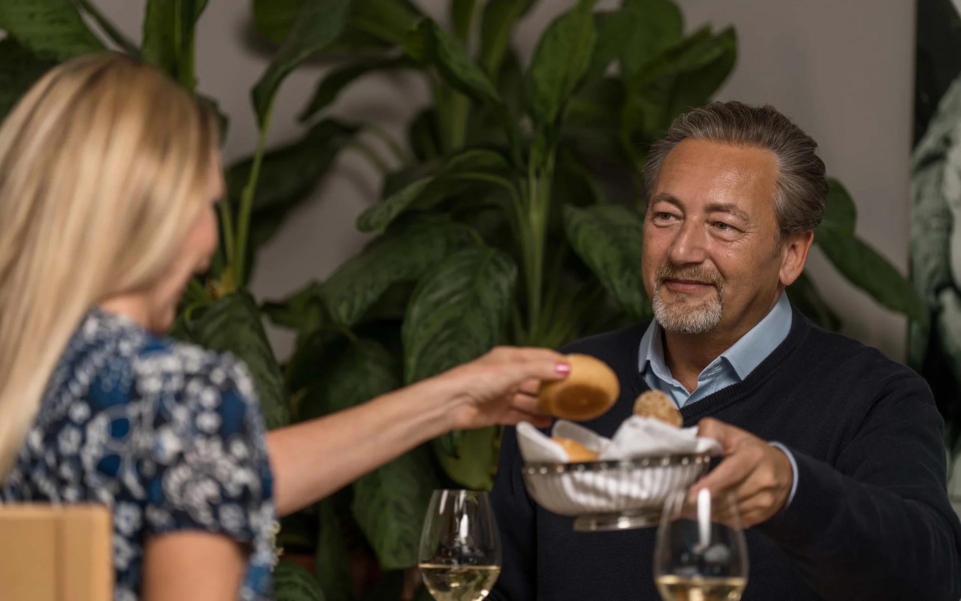 Mann reicht Frau einen Brotkorb beim gemeinsamen Essen