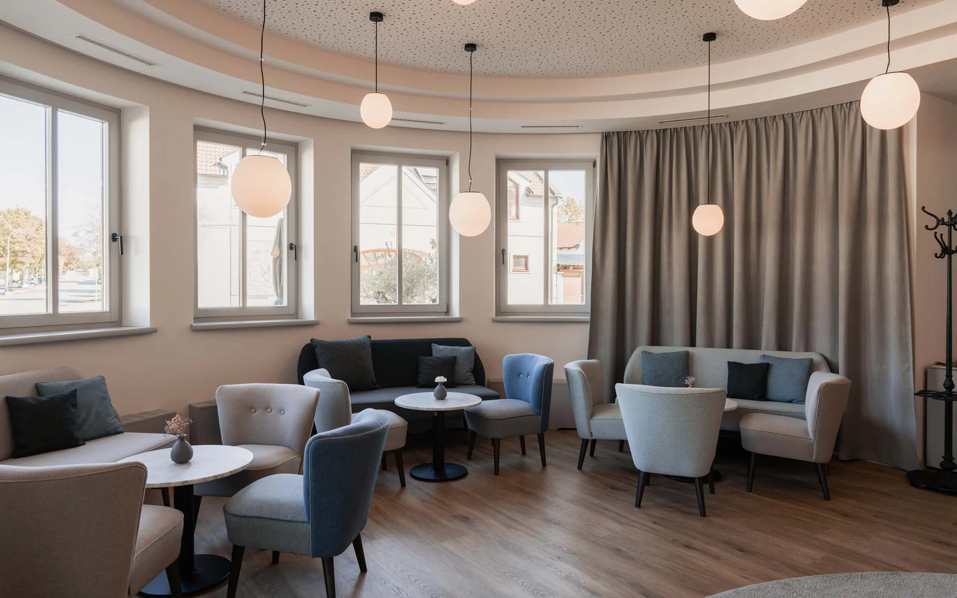 Moderner Wartebereich mit Sesseln, Sofas und runden Tischen unter hängenden Lampen