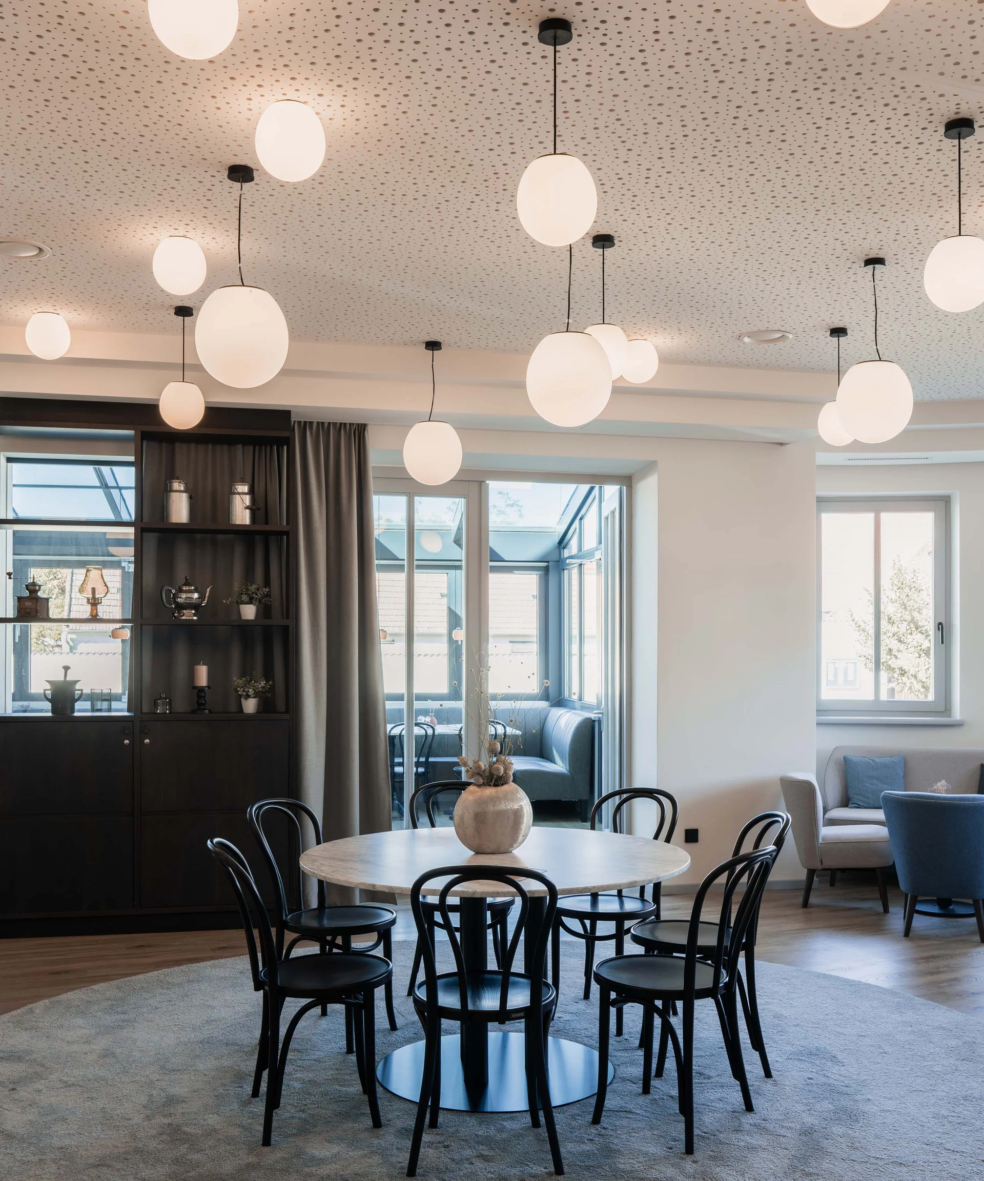 Luis von Weyden: your stylish guesthouse in Weiden am See Modern dining area with round table, black chairs, and round ceiling lights