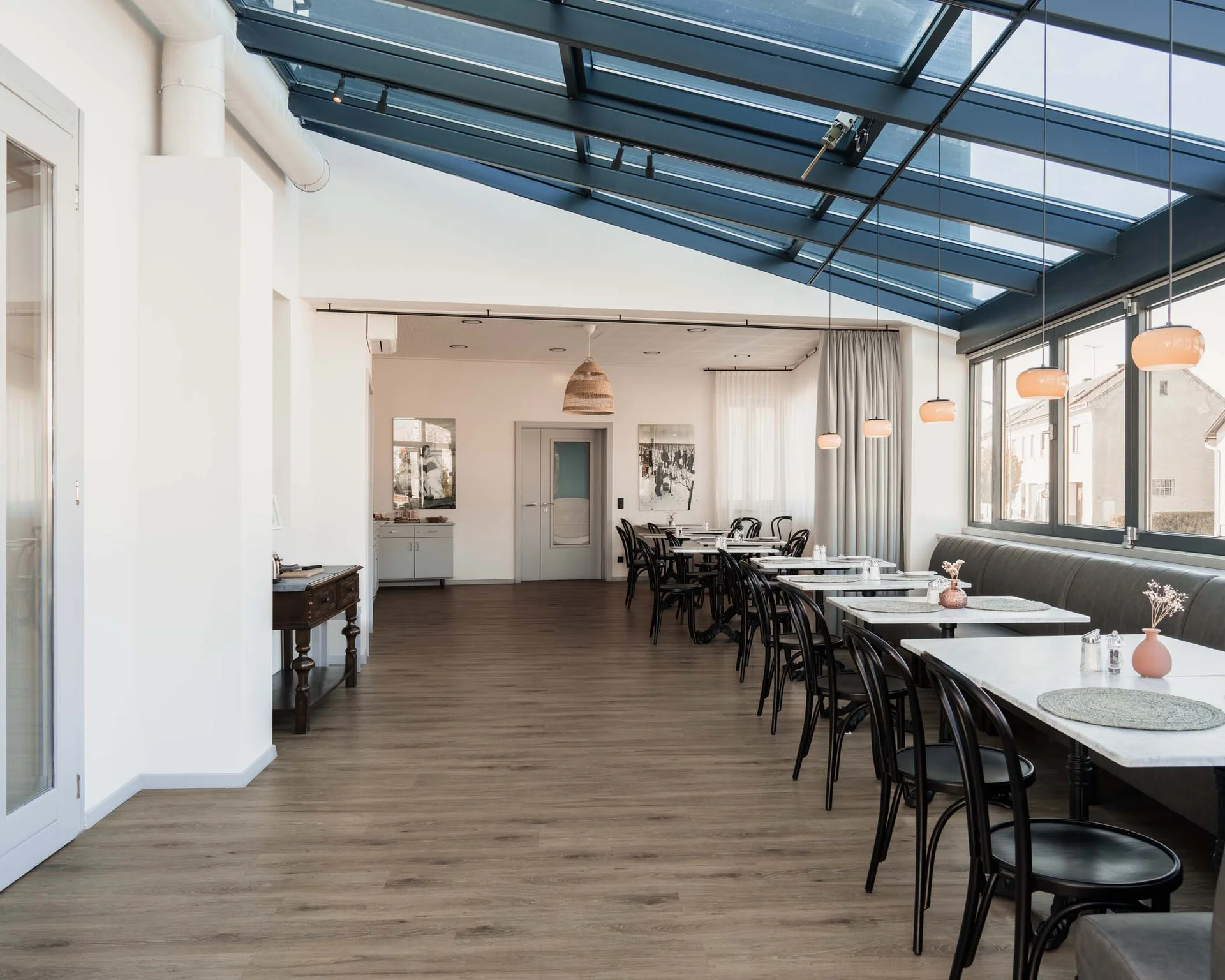 Moderner heller Speiseraum mit Glasdach und Tischen an Fenstern