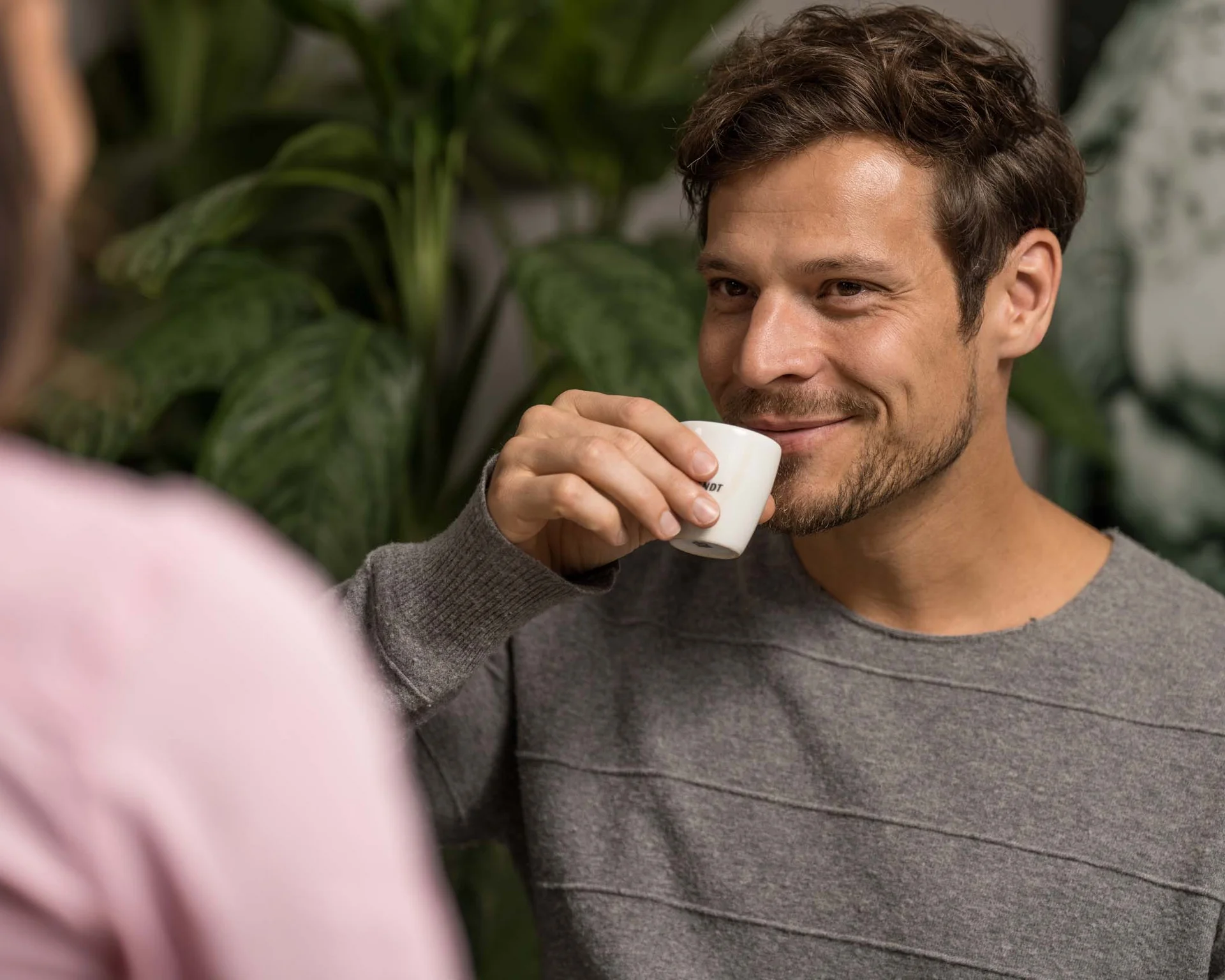 Mann trinkt Kaffee und lächelt in einem grünen Raum
