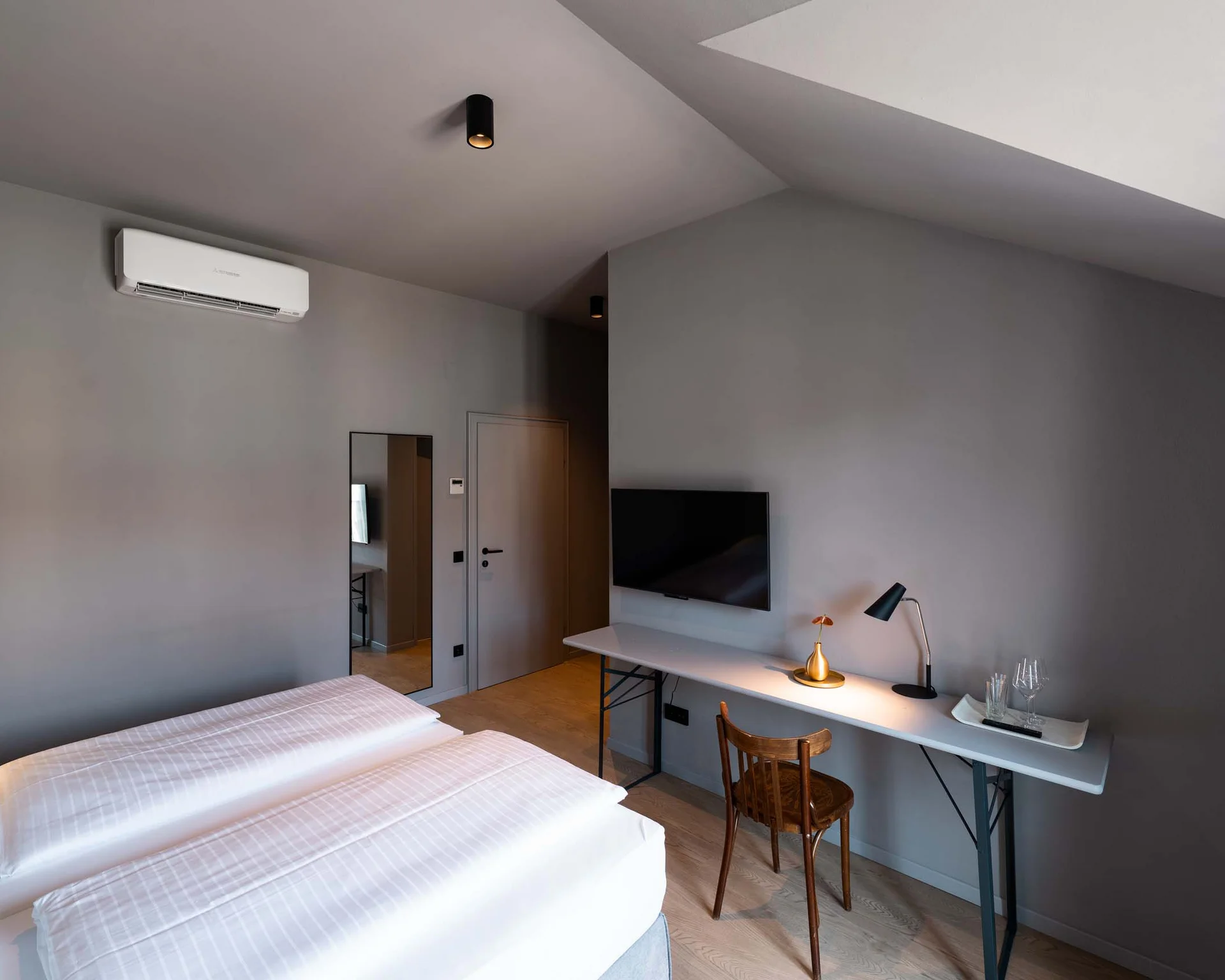 Modernes Hotelzimmer mit Doppelbett, Schreibtisch, Fernseher und Klimaanlage