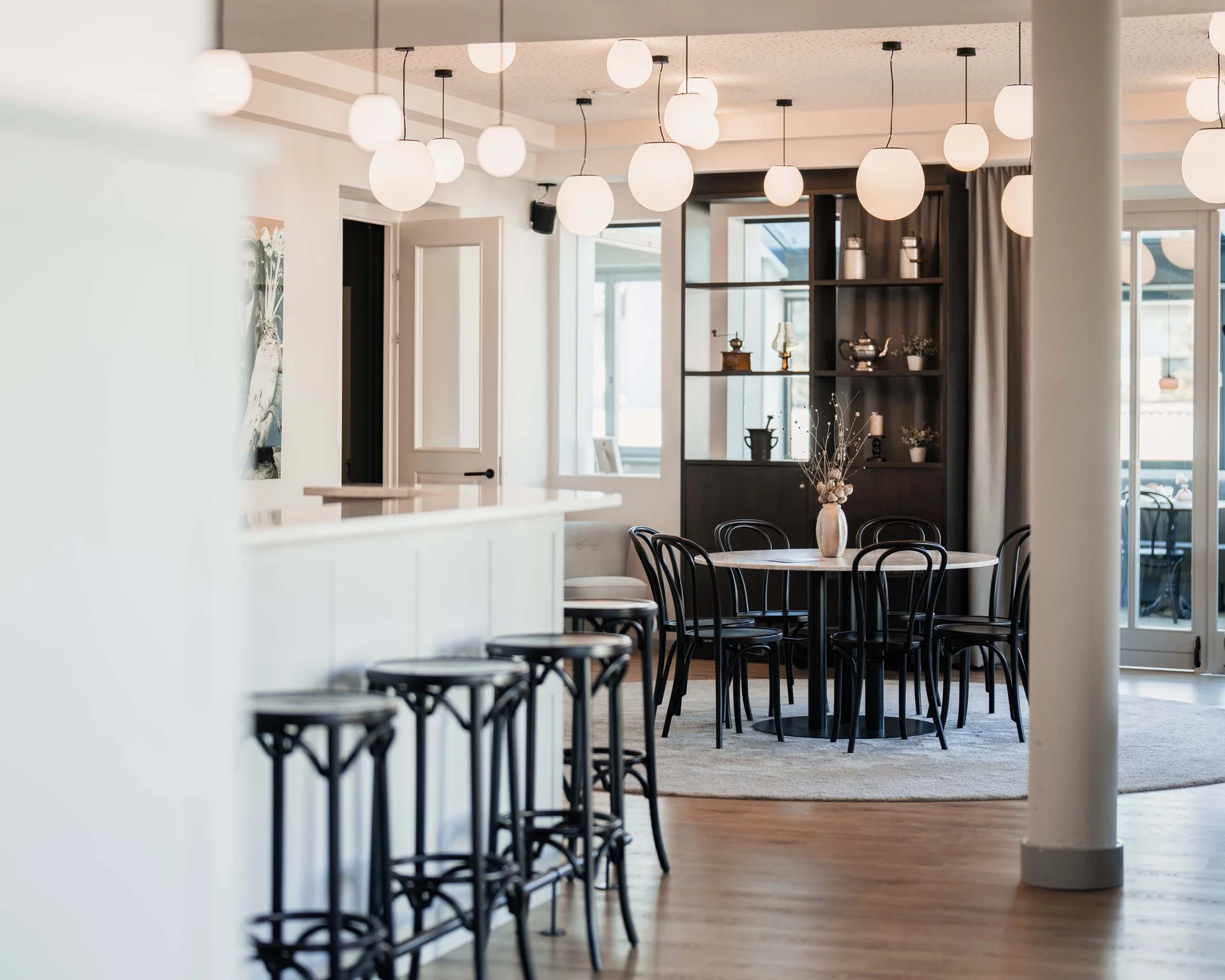 Moderner heller Gastraum mit schwarzen Stühlen und rundem Tisch