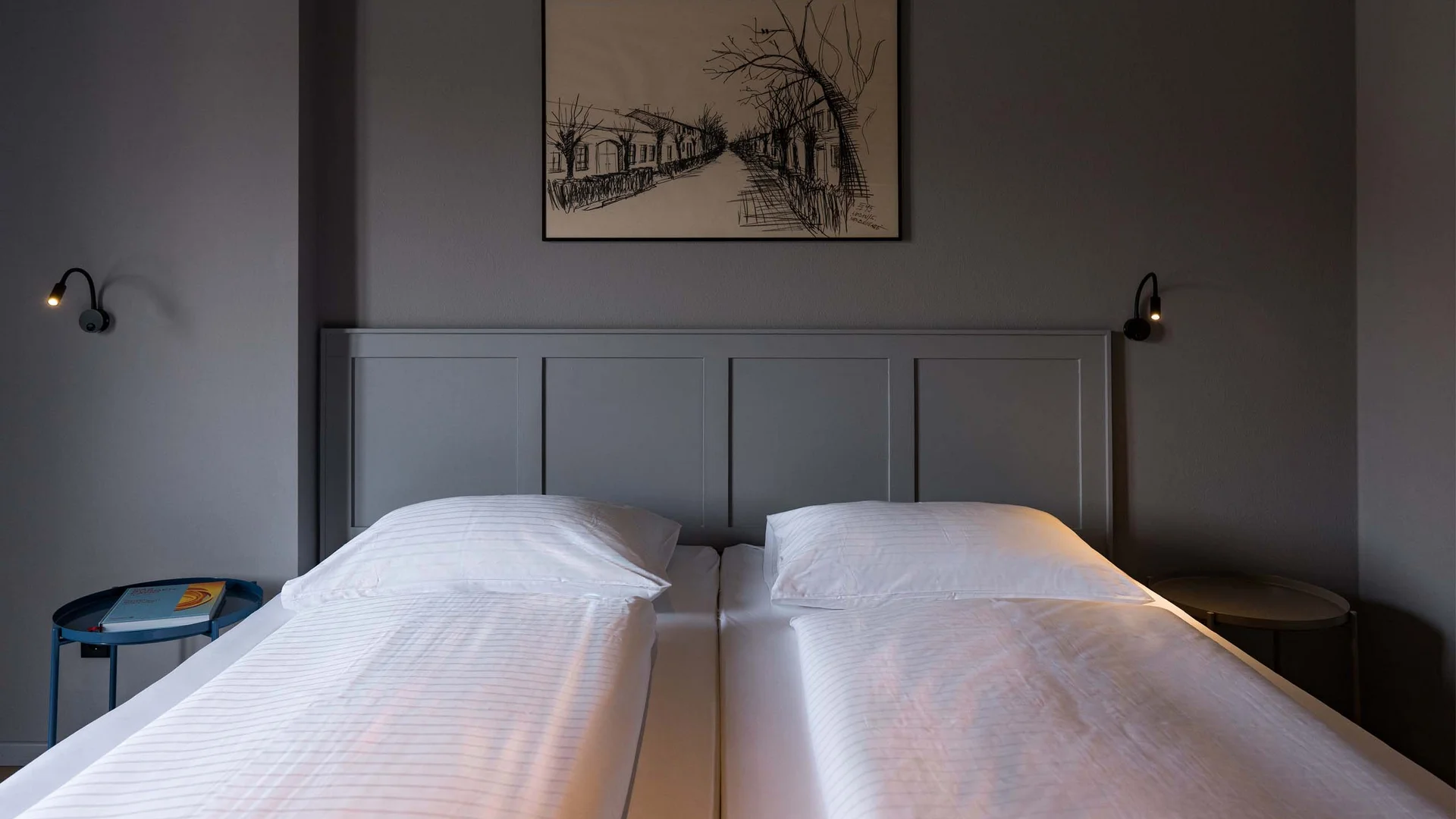 Unser Hotel in Weiden am See: ein Schmuckstück Zweibettzimmer mit weißen Betten, grauer Wand und schwarzem Wandbild