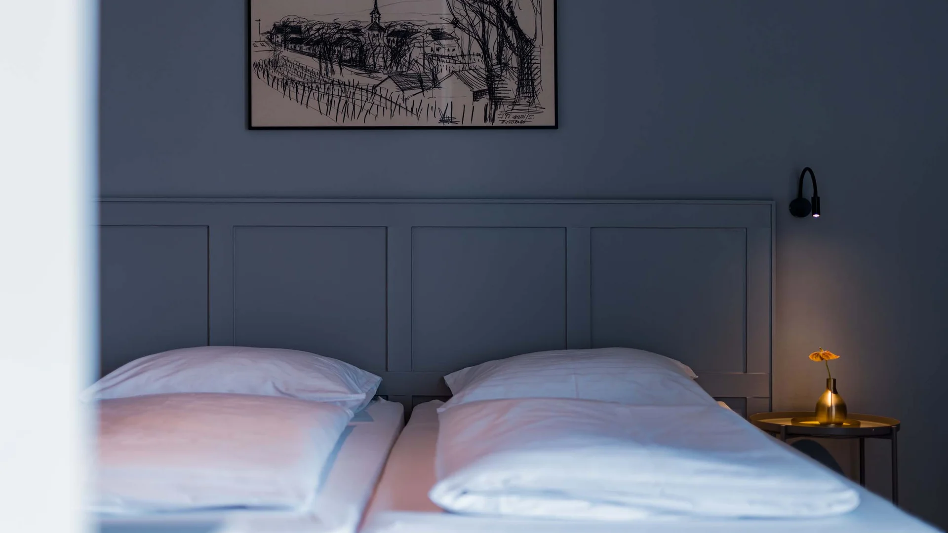 Gemütliches Schlafzimmer mit zwei Betten, kleinem Nachttisch und Wandbild