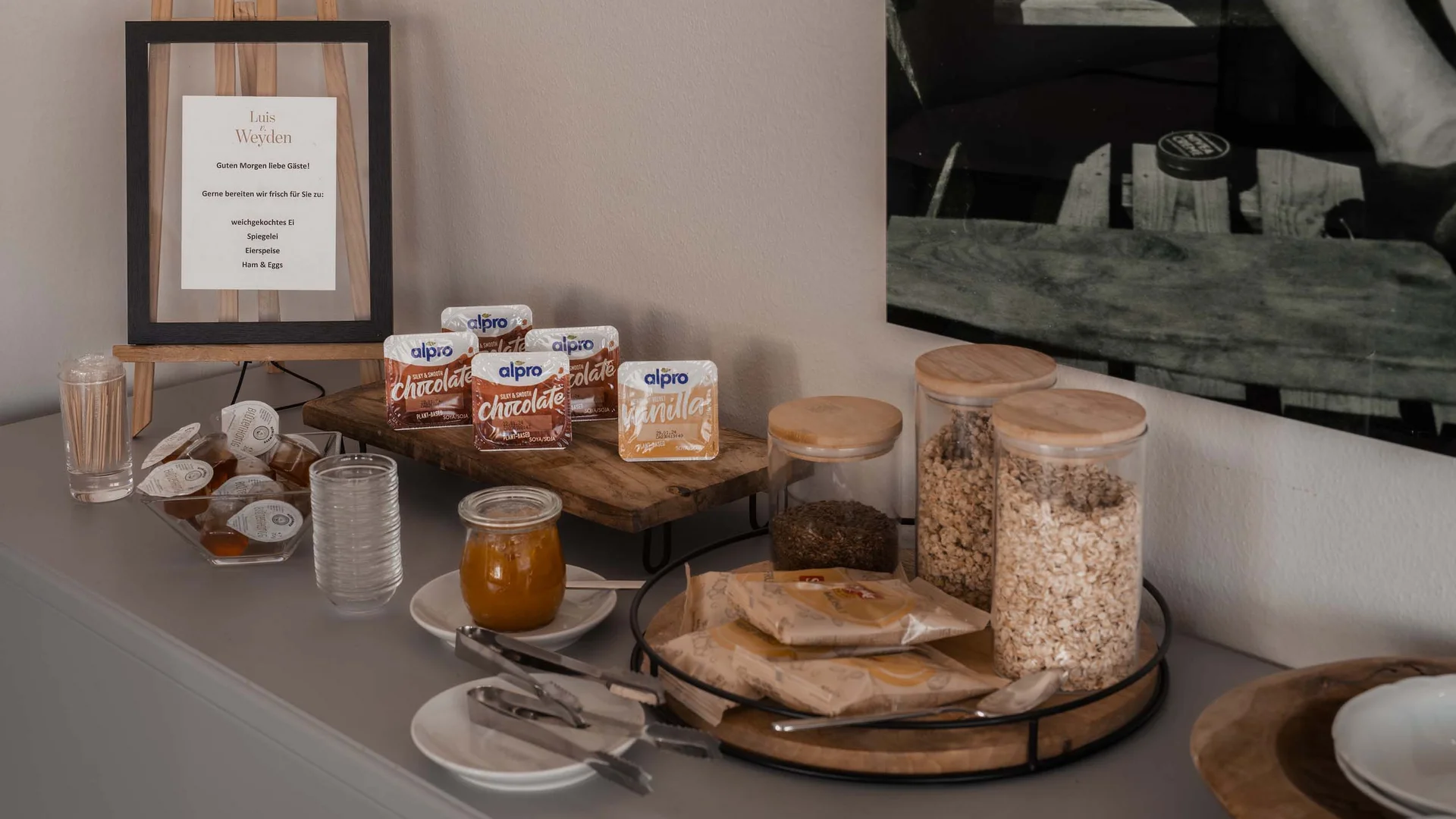 Frühstücksoptionen mit Müsli, Alpro-Getränken und Marmelade auf Anrichte