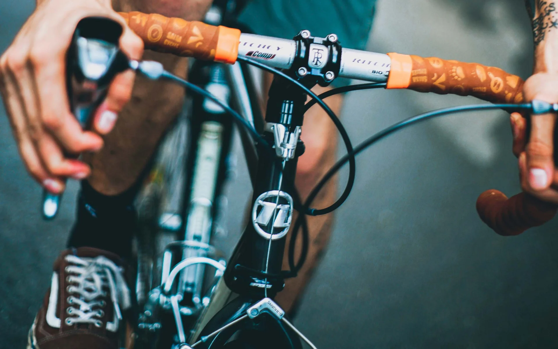 Mann mit Tattoos fährt Fahrrad und trägt rotes T-Shirt und grüne Shorts