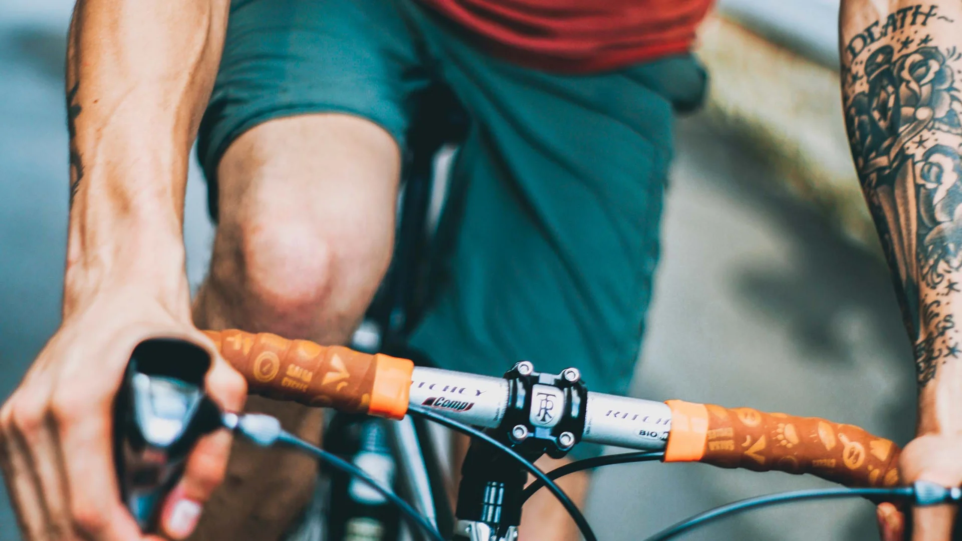 Neusiedler See Radweg: Übernachtung im Luis von Weyden Mann mit Tattoos fährt Fahrrad und trägt rotes T-Shirt und grüne Shorts