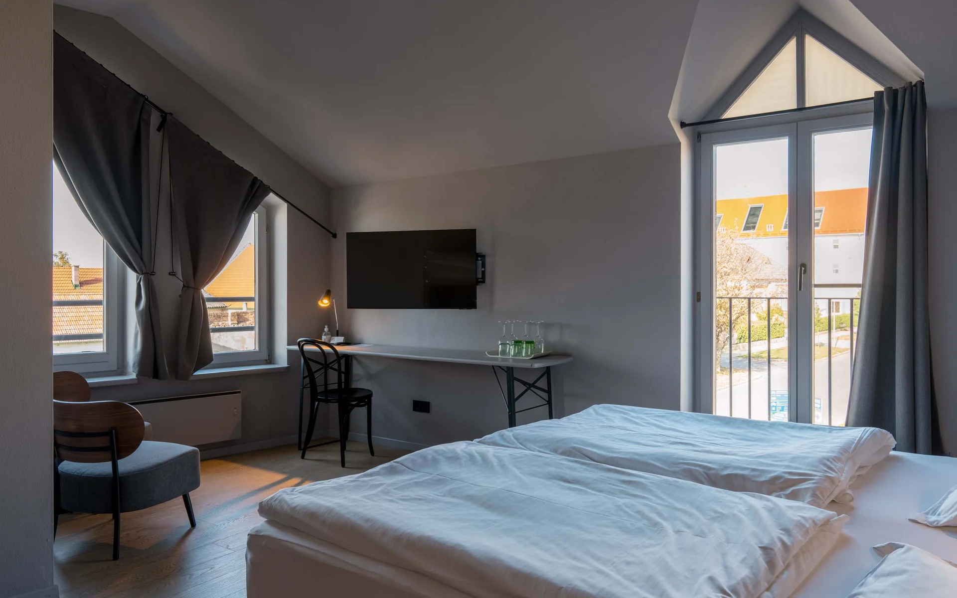 Luis von Weyden: your stylish guesthouse in Weiden am See Bright hotel room with double bed, desk, chair, and balcony windows