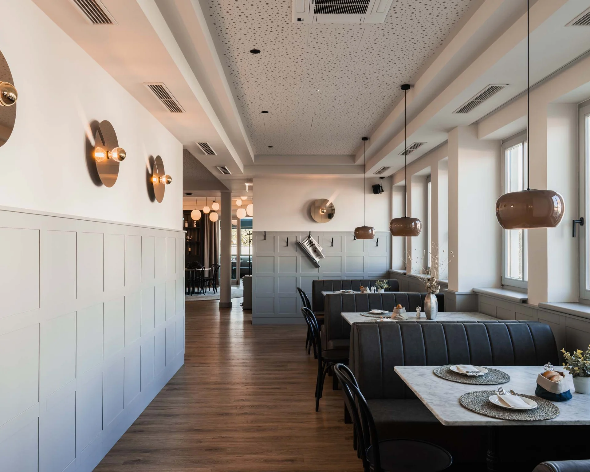 Modernes Restaurant mit Sitzbänken, Tischen und großen Fenstern