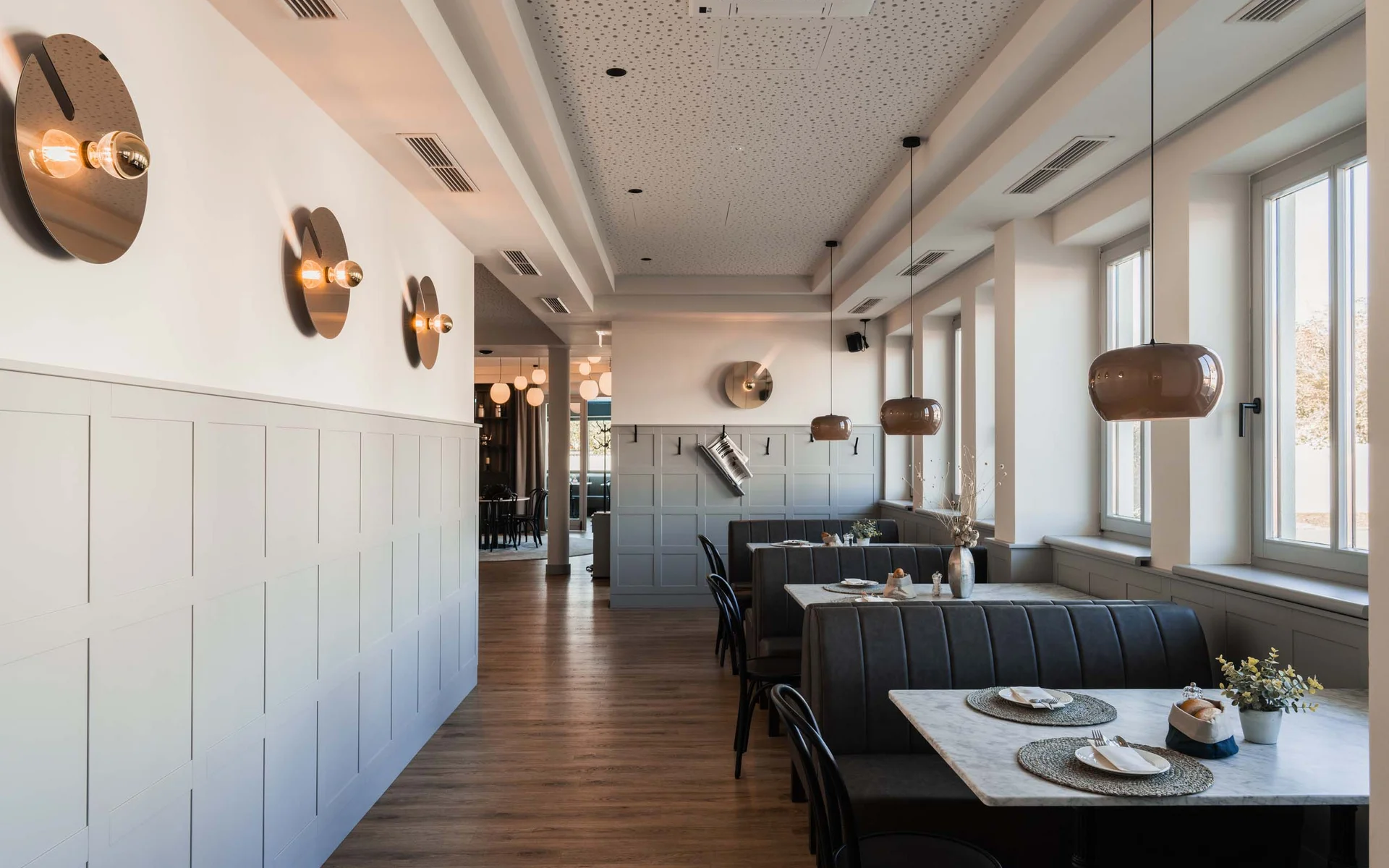 Modernes Restaurant mit Sitzbänken, Tischen und großen Fenstern